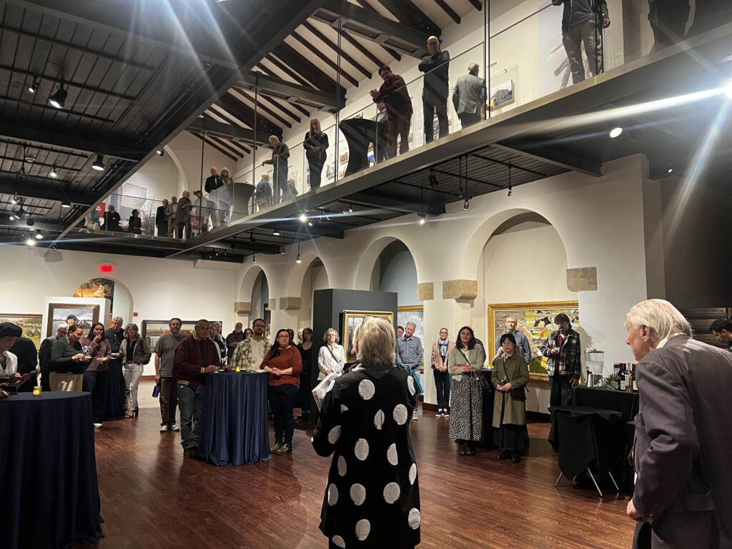 Photographer and author, William Brumfield, stands in the far right before a crowd at Avant-garde Architecture of the Soviet Era: Photography by William Brumfield exhibit at The Museum of Russian Art.